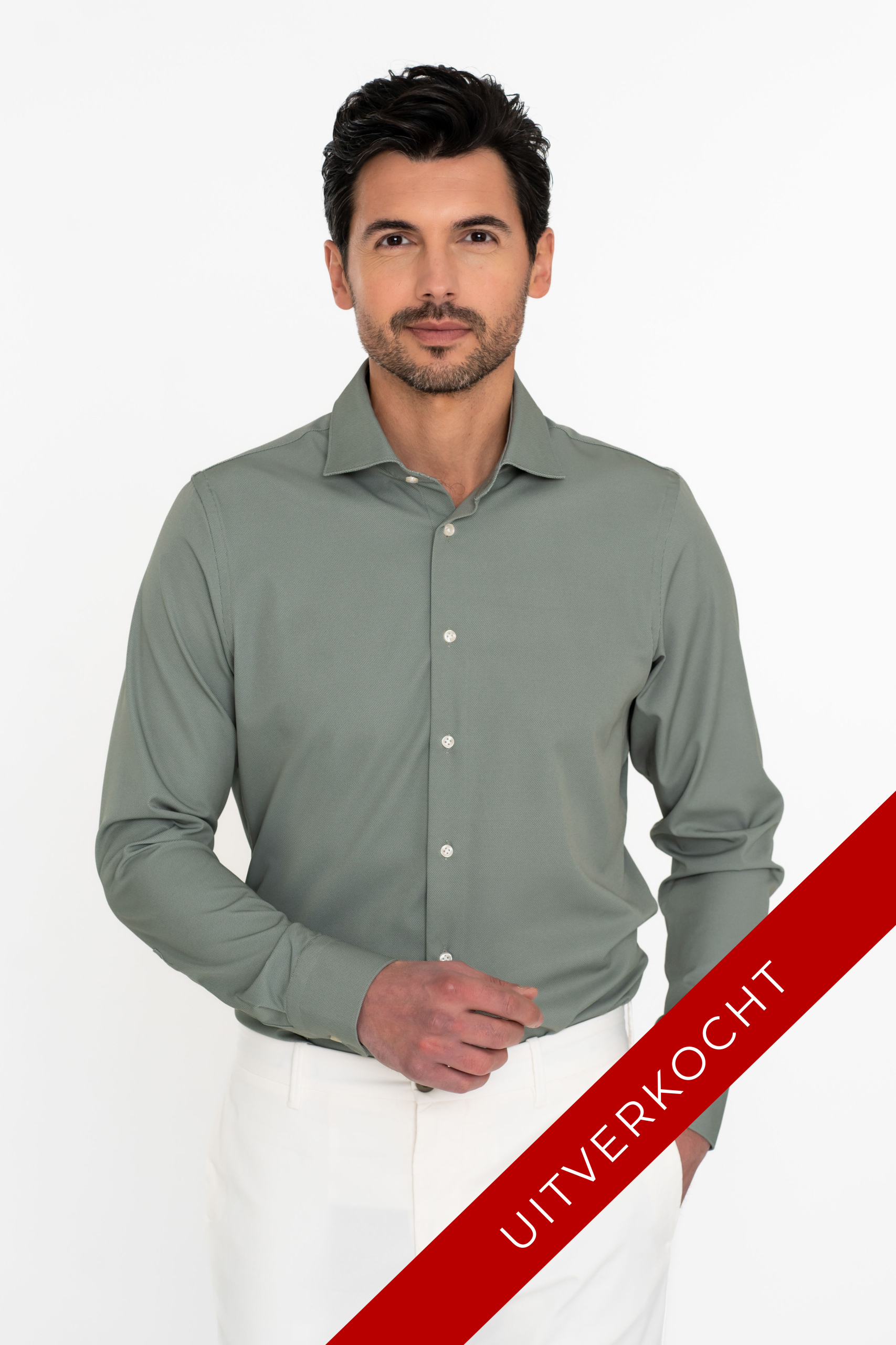 Jongeman met kort getrimd baardje in een groen techno comfort overhemd op een witte broek.
