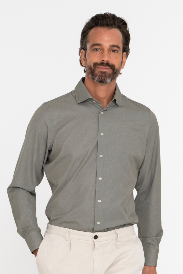 Vriendelijke man met baard in groen techno comfort shirt op lichte chino chino broek.
